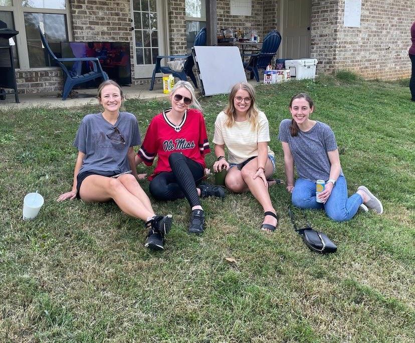 group of four pediatric residents siting on gras at outdoor event